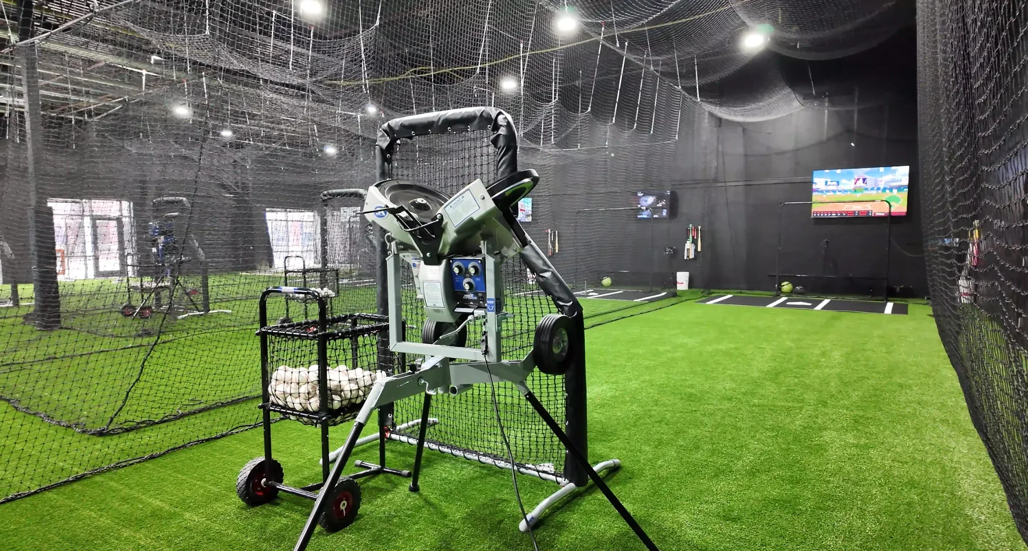 Conventional automated pitching machine in a training batting cage